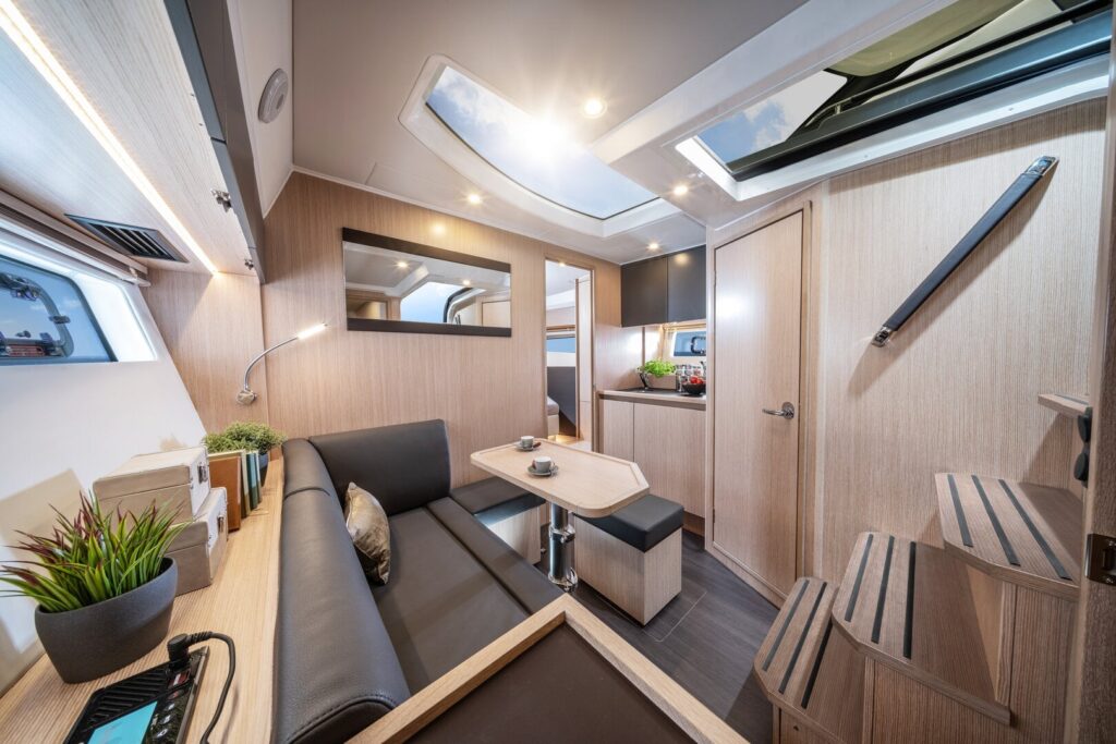 Motoryacht chartern in Neustadt in Holstein: Der moderne, lichtdurchflutete Salon mit Sitzecke und Pantry unter Deck der BAVARIA SR38 bei Hanse Yachtcharter.